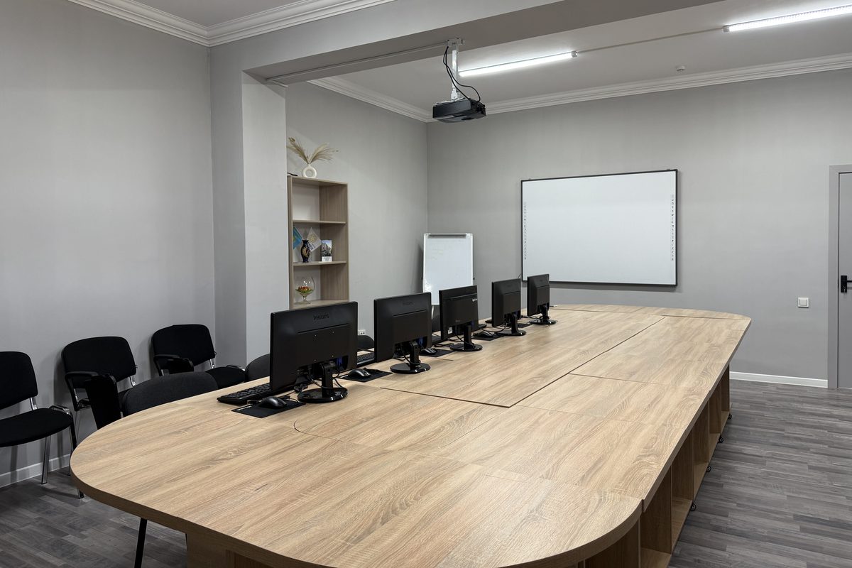 Класс Open Consulting: компьютеры на общем столе, проектор под потолком, интерактивная доска и флипчарт