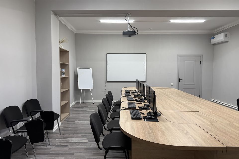 Учебный класс Open Consulting: длинный стол с компьютерами, проектор и интерактивная доска